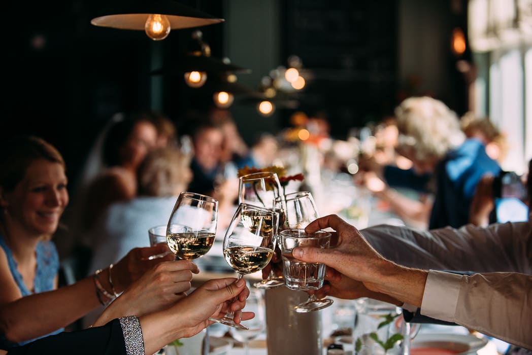 Hands toasting wine glasses, with blurry lights in the background