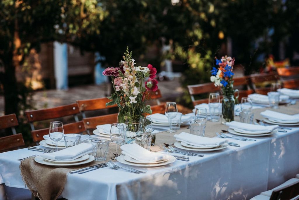 Outdoor dinner table set with plates, cutlery and colorful wildflowers in a rustic wedding venue in the Netherlands