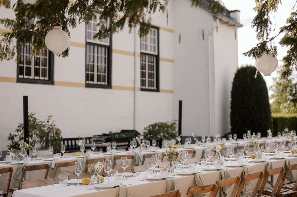 Two long dinner tables in the courtyard of Slot Doddendael, with the white walls of the castle in the background