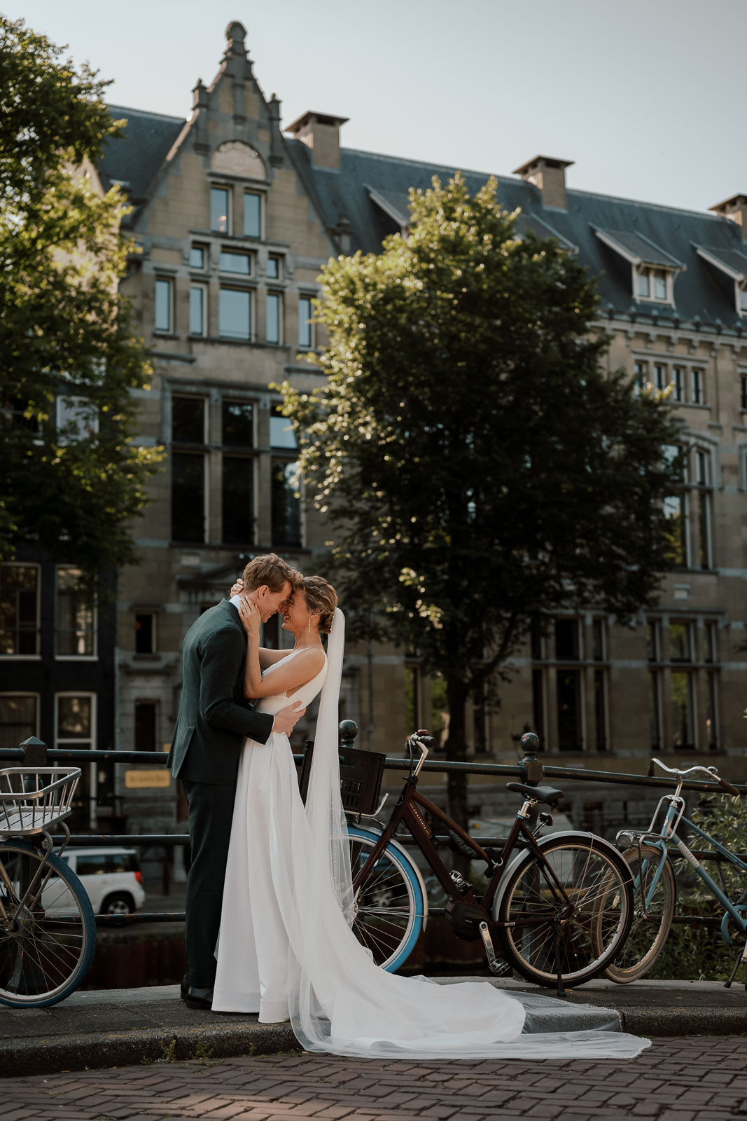 wedding and elopement services, Bride and groom embracing on a canal bridge in Amsterdam, with bicycles and historic architecture in the background.