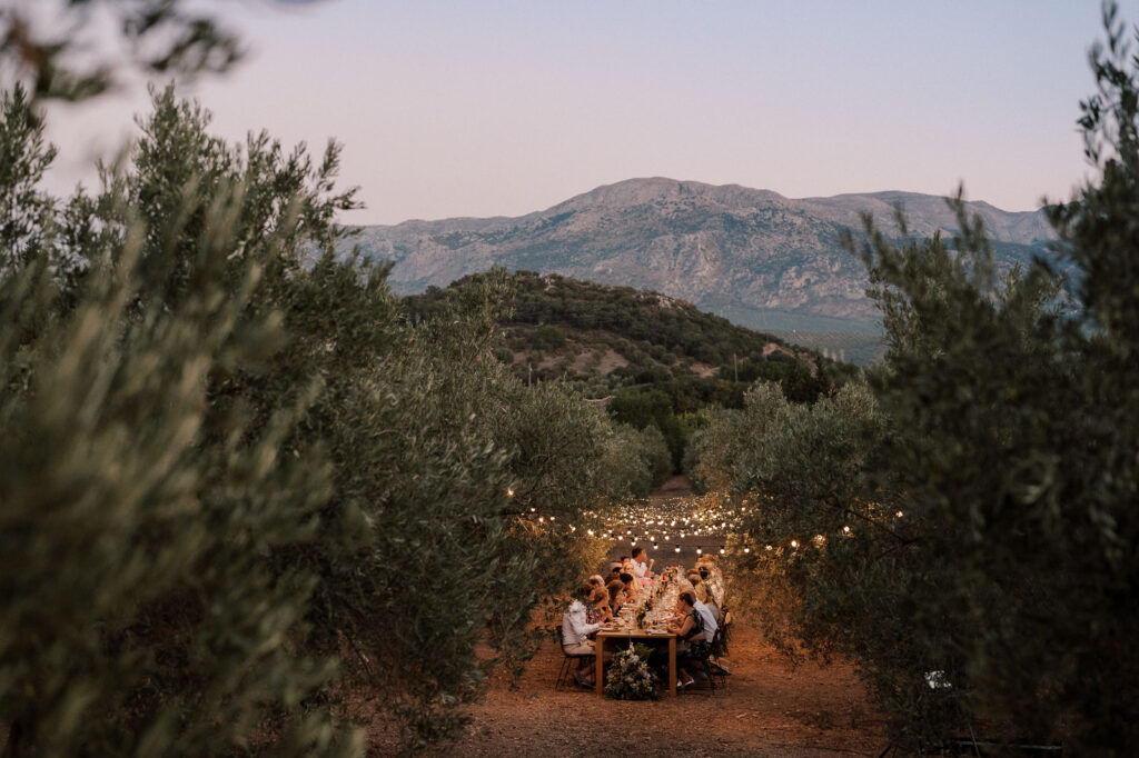 Wedding party having an outdoor dinner during sunset, with rugged mountains in the background