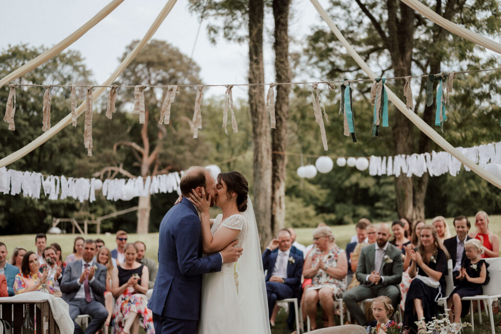 Bride and groom sealing their marriage with a kiss, at an outdoor wedding venue in Belgium