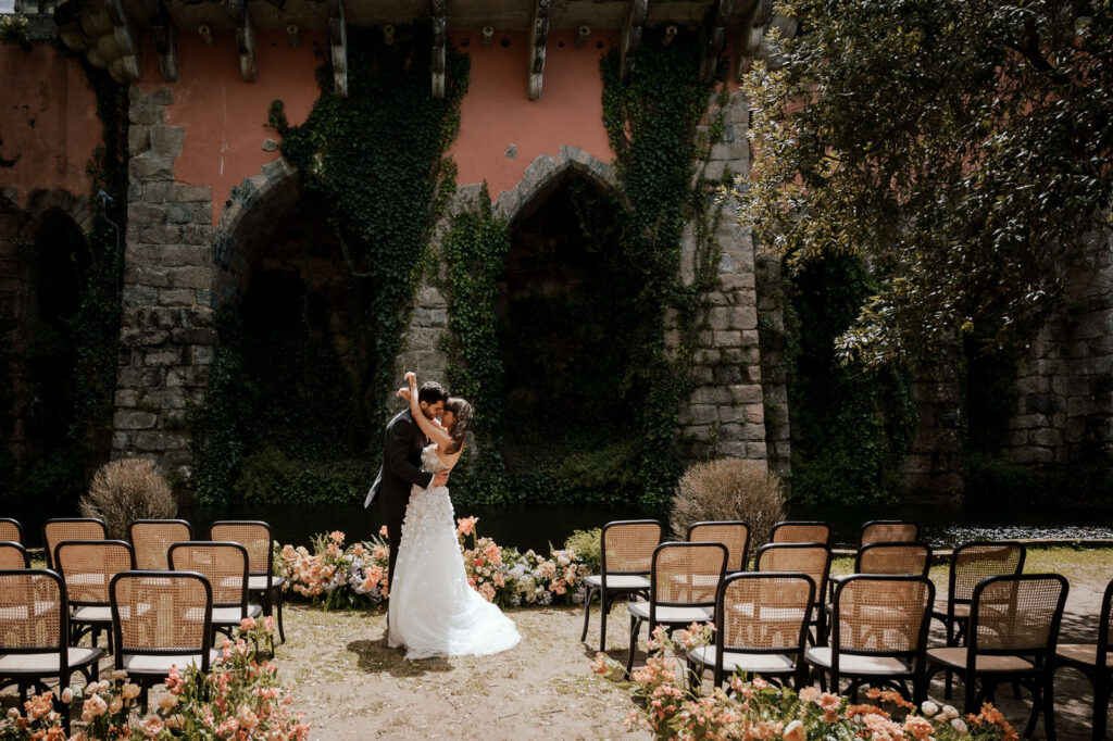 Wedding couple holding each other in a fairy-tale destination in Portugal, against the backdrop of a historic mansion