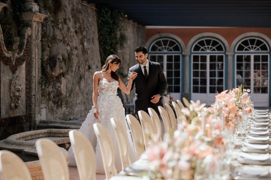 Bride and groom holding hands and smiling happily at an elegant outdoor wedding venue in Portugal