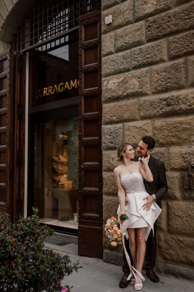 Wedding & Elopement Photographer, Couple posing against large brick wall while looking at each other