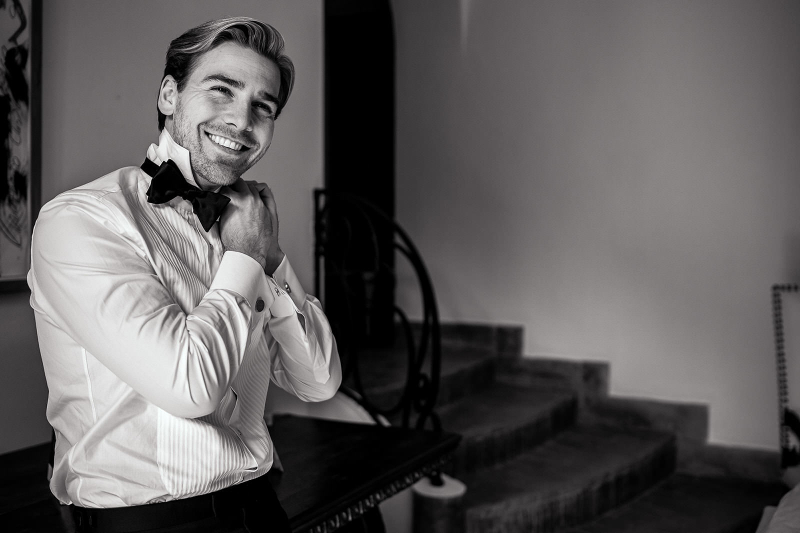 smiling groom adjusting bowtie