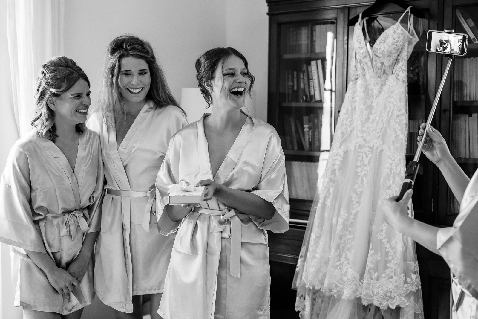 wedding and elopement photographer bridesmaids laughing together while taking selfie with wedding dress