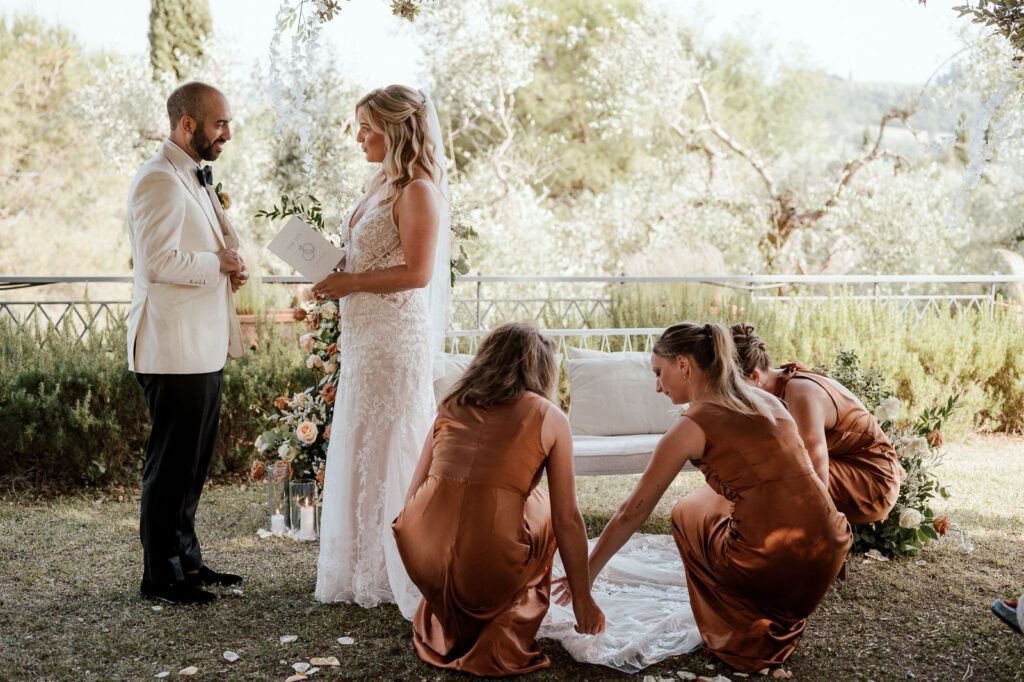 wedding and elopement photographer, bridesmaids adjusting the dress while couple is reading vows