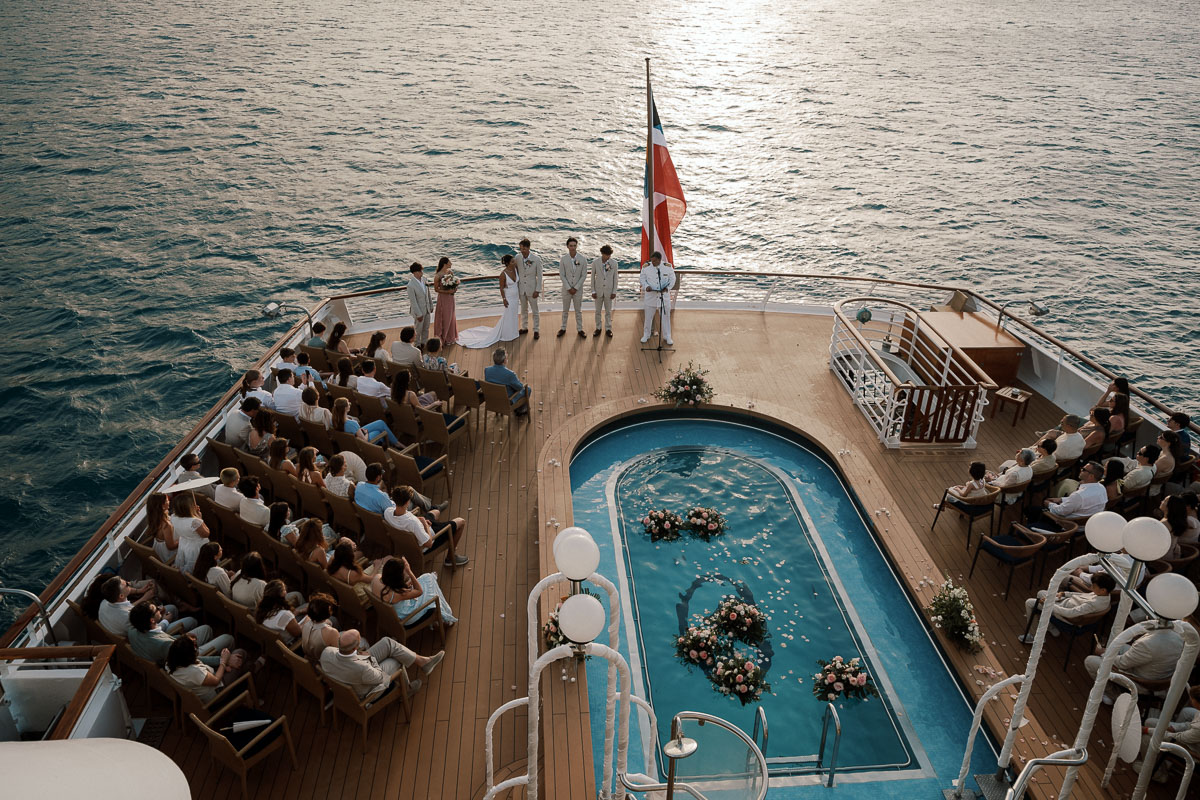 Wedding ceremony on a private yacht in the Caribbean with guests gathered on deck at sunset